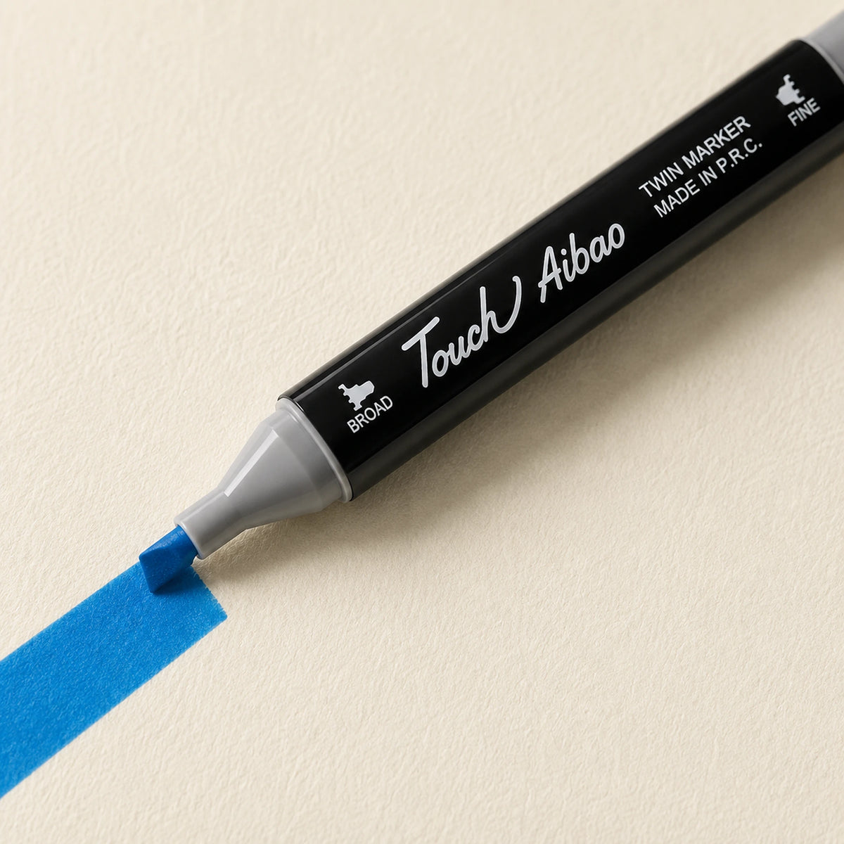 Broad chisel nib of a Touch Aibao marker laying a wide Cerulean Blue stroke across ivory art paper