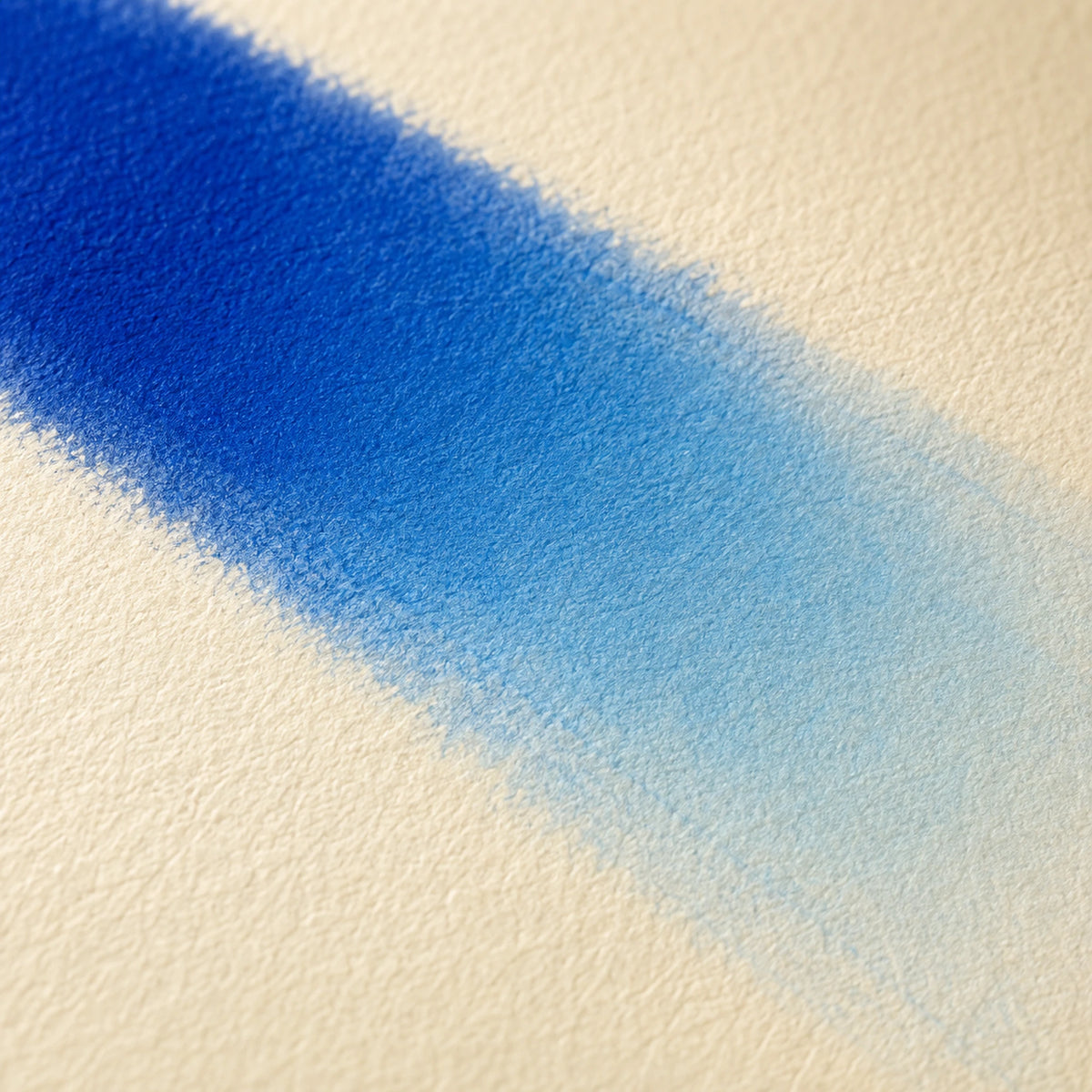 Close macro of alcohol ink blending from Cobalt Blue into Cerulean Blue in one seamless band on ivory art paper